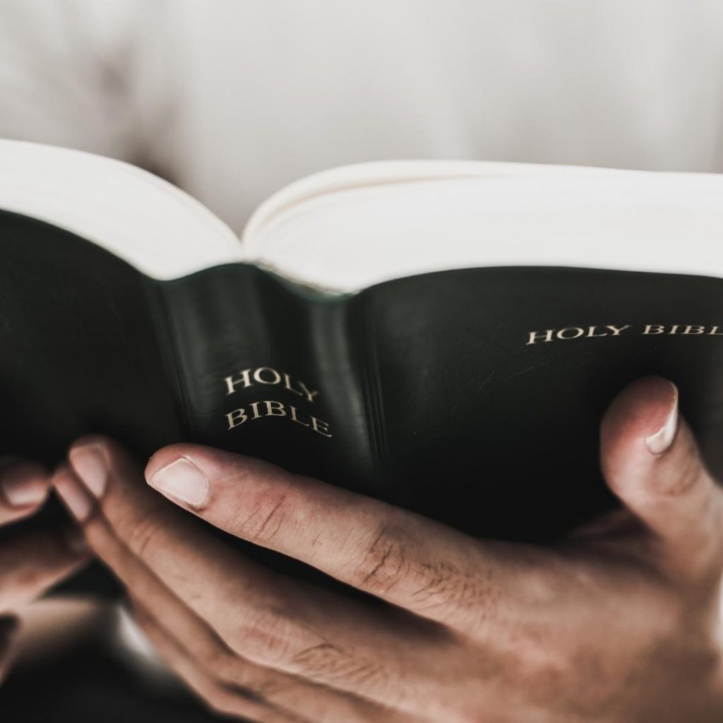 close up of hands holding a bible